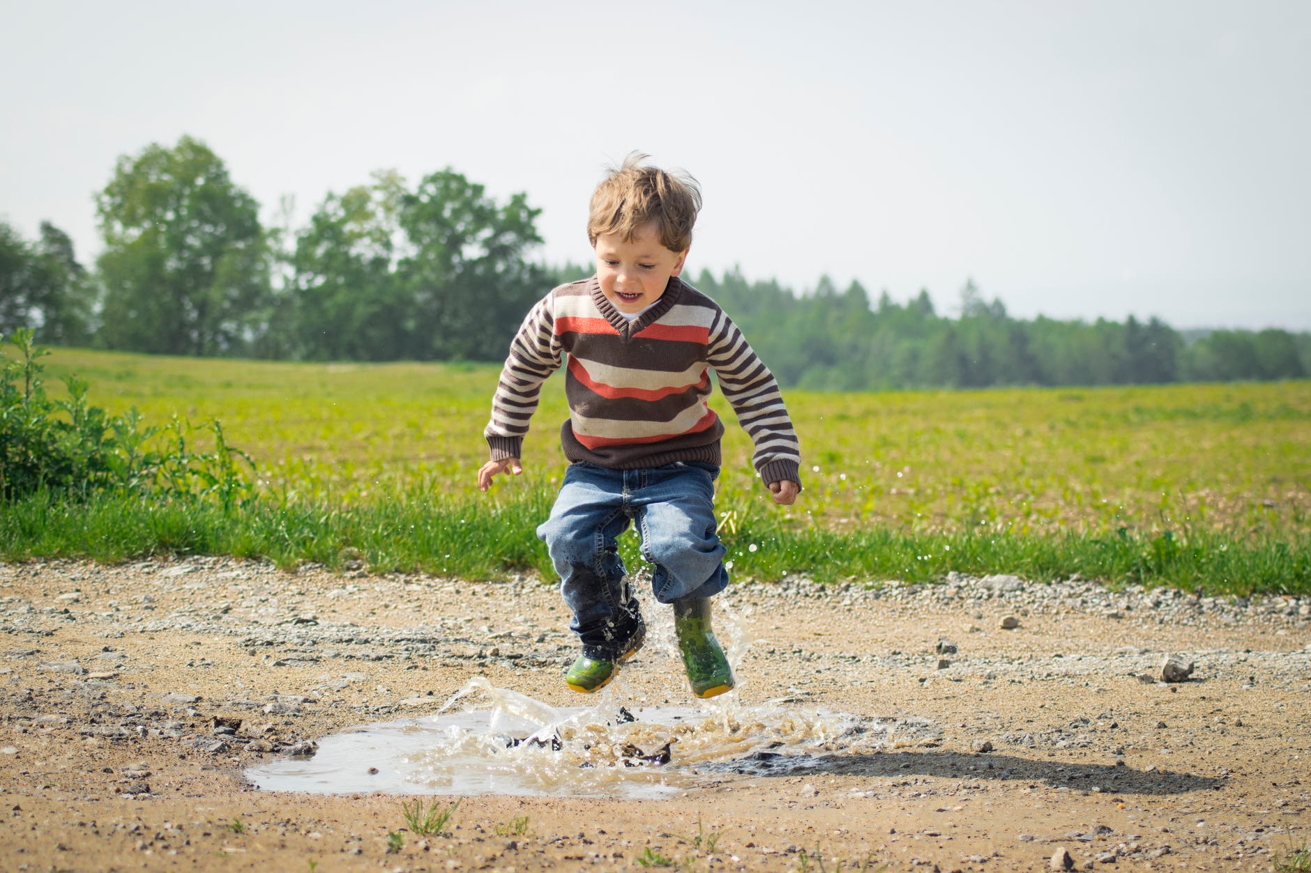 boy jumping near grass at daytime